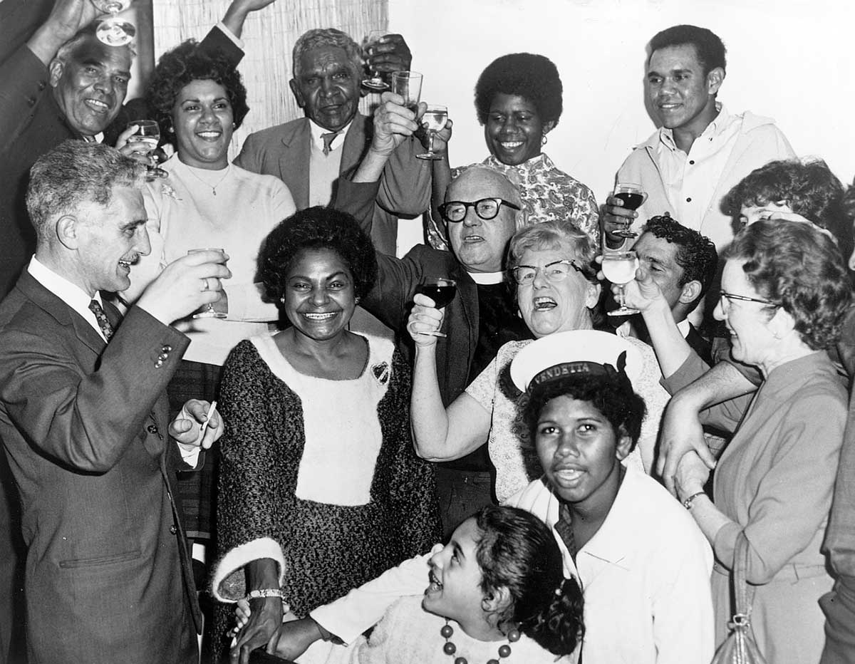 Black and white photo of a group of people celebrating and making toasts. - click to view larger image