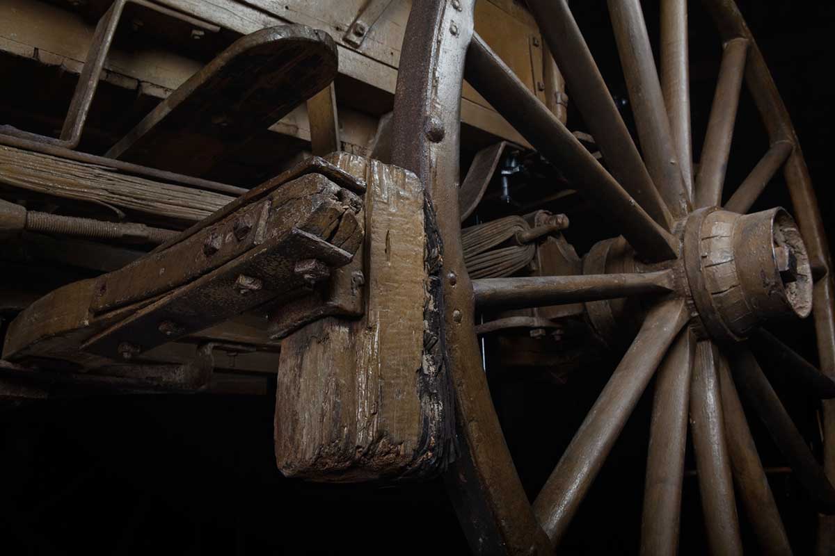 Detail showing part of the rear wheel and undercarriage of a wooden mail coach.
