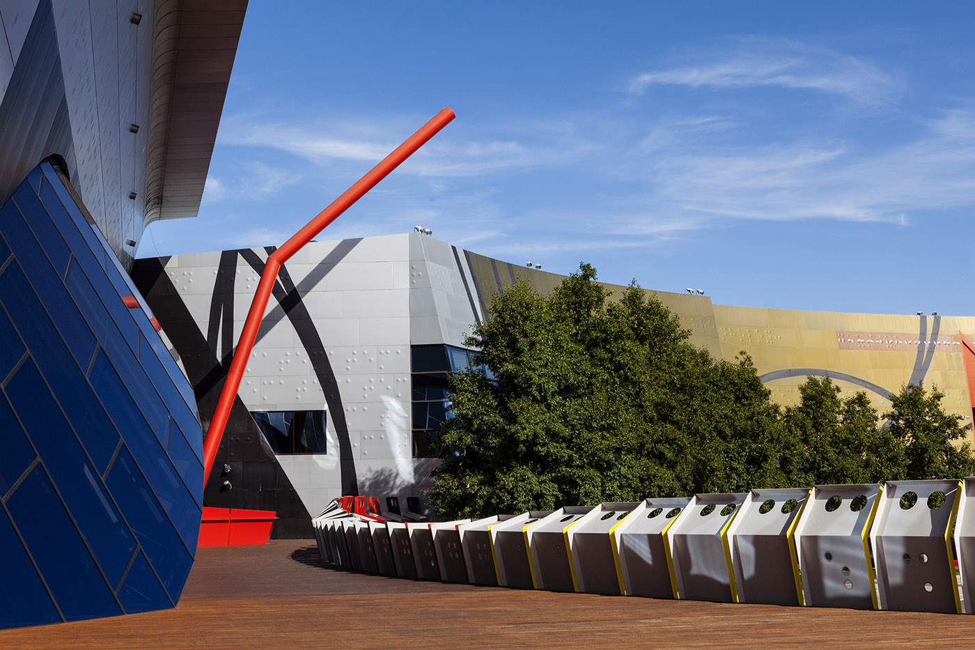 Photograph of the National Museum of Australia's Straw Deck. The deck is wooden with a large metal architectural feature that looks like a straw rising through the deck and into the air.