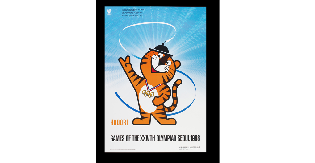 This poster is a promotional image for the 1988 Seoul Summer Olympics. The central figure is a cheerful cartoon of a tiger, coloured in orange with black stripes, a white stomach and a friendly smile. The tiger is wearing a traditional Korean hat called a sangmo, and its right paw is raised in a peace sign. Around the tiger's neck are Olympic medals with a blue and red ribbon.  The background features a radiant blue, with a pattern of rays and circular gradients.