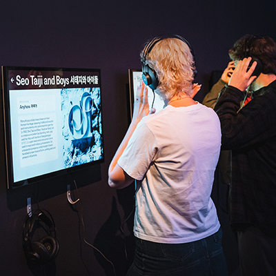 Two people listening to audio whilst watching a screen.