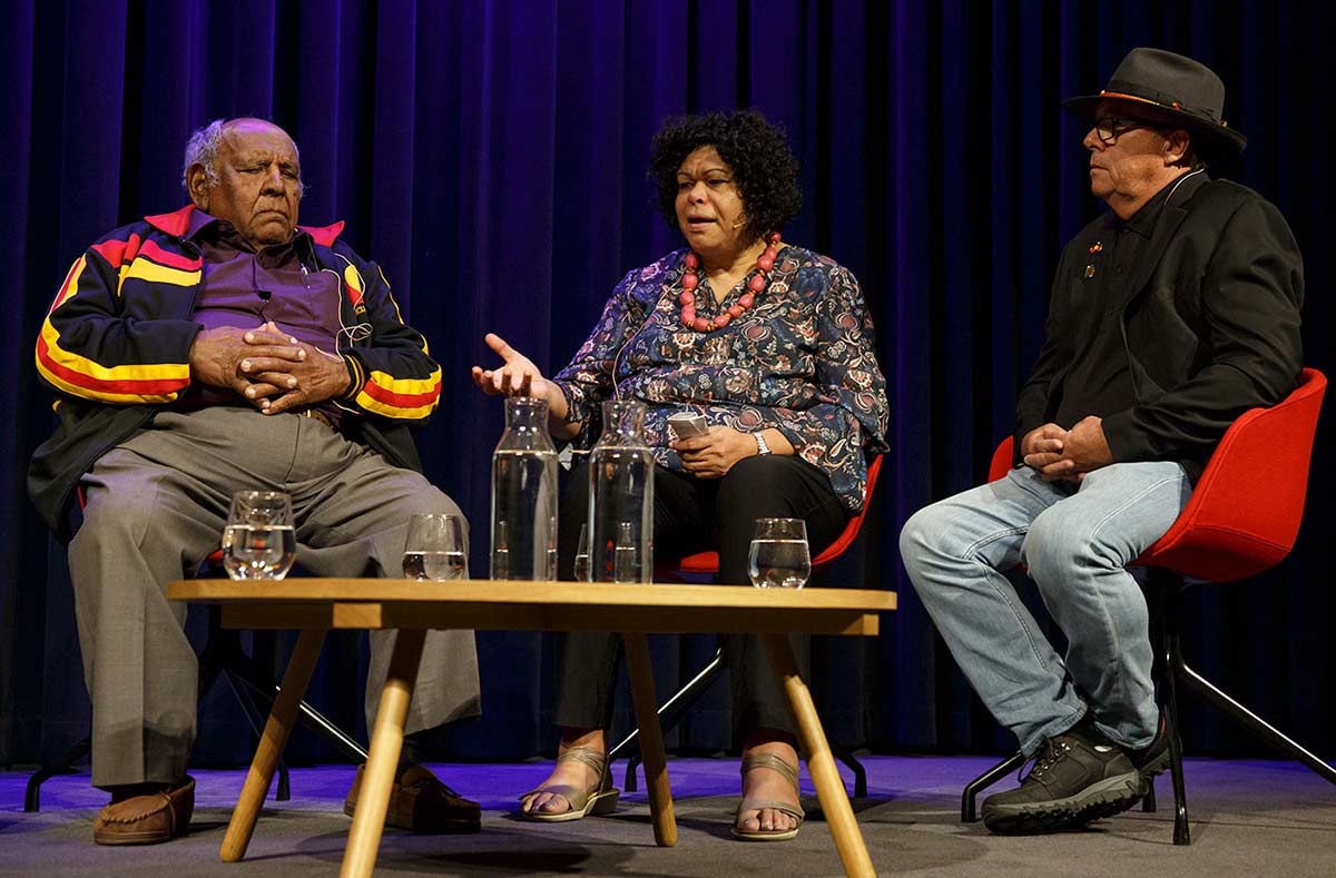 Two men and one woman sitting on a stage in discussion