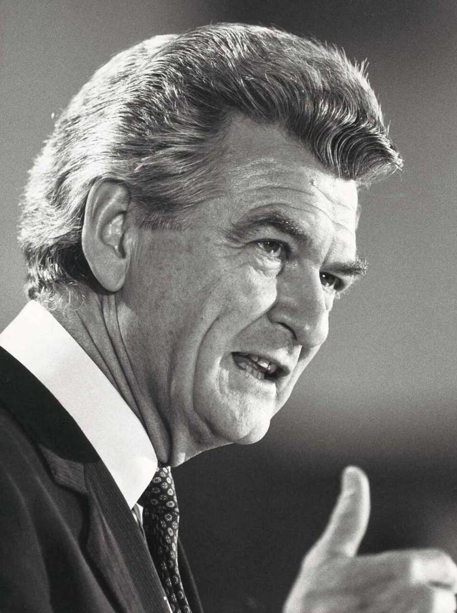 Black and white three-quarter profile photo of Hawke speaking publicly. - click to view larger image