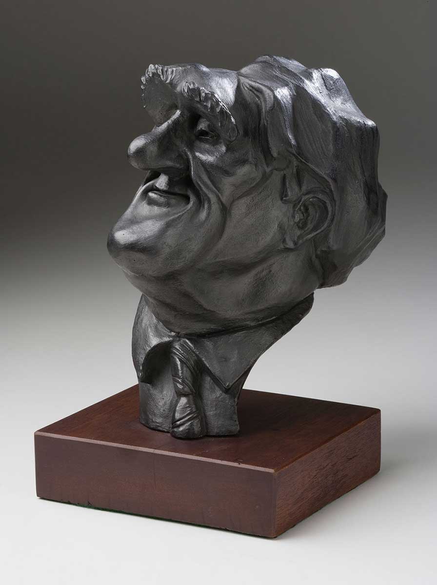 Sculpture titled 'The Dismissal - 20th Anniversary' by John Shakespeare. Three-dimensional comical figures of Opposition Leader Malcolm Fraser, Governor General Sir John Kerr, and Prime Minister Gough Whitlam are mounted on a piece of black painted board. The figure of Kerr is about to club Whitlam with a bottle of Champagne, while Fraser holds Kerr's coat tails. - click to view larger image