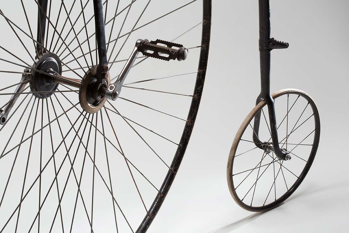 Close up image showing the smaller rear wheel and part of the front wheel and pedals of a penny-farthing bicycle. - click to view larger image