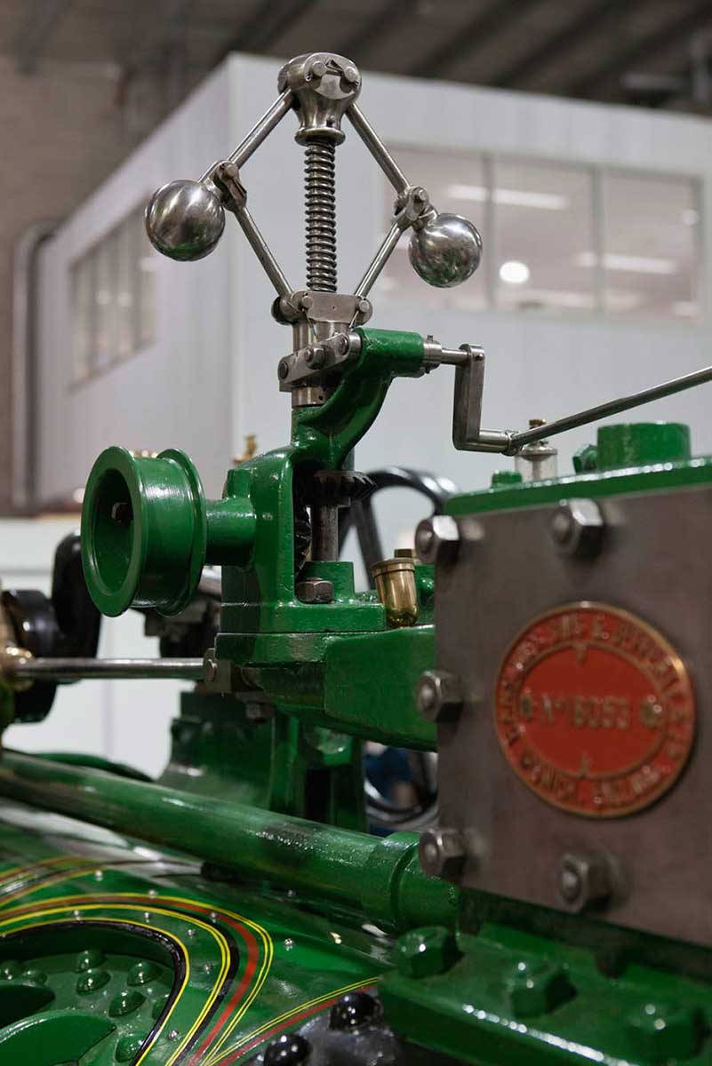 A colour photograph showing part of the top of a steam engine, including the serial plate and governor. - click to view larger image