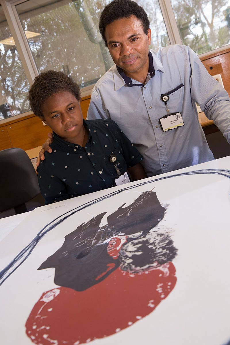 Man with boy inspecting artwork - click to view larger image