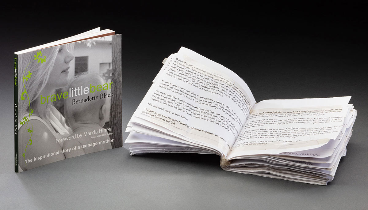 Book standing beside the open pages of a typed manuscript. - click to view larger image