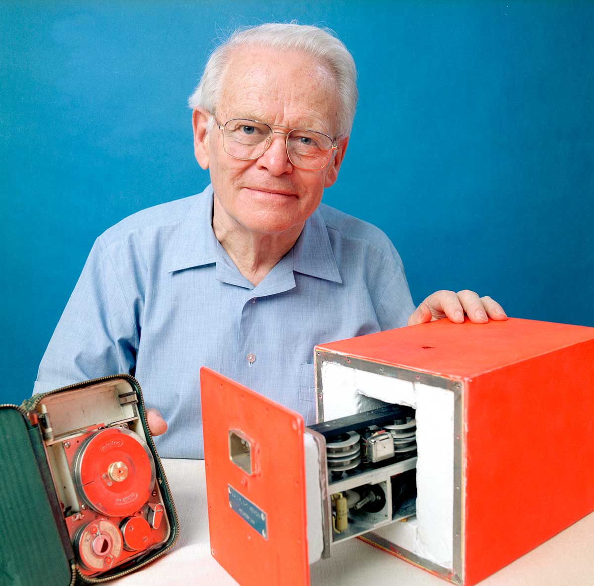 An elderly gentleman posing with two orange devices.