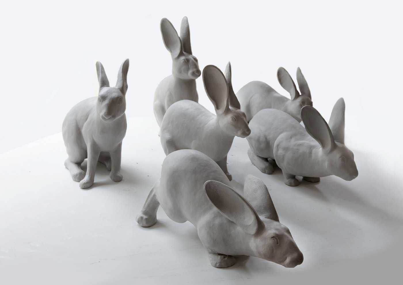 Six matt white ceramic figures modelled on the European wild rabbit. - click to view larger image