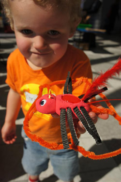 A colour photograph of a boy holding a bright orange and grey craft item.