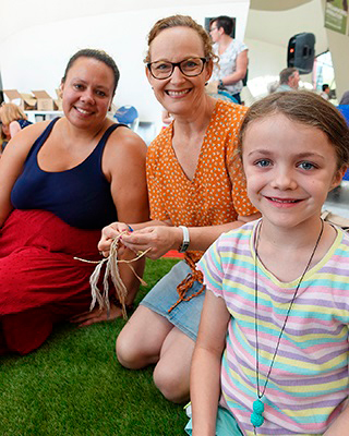 Two women and a young girl participating in a craft activity at the Museum.
