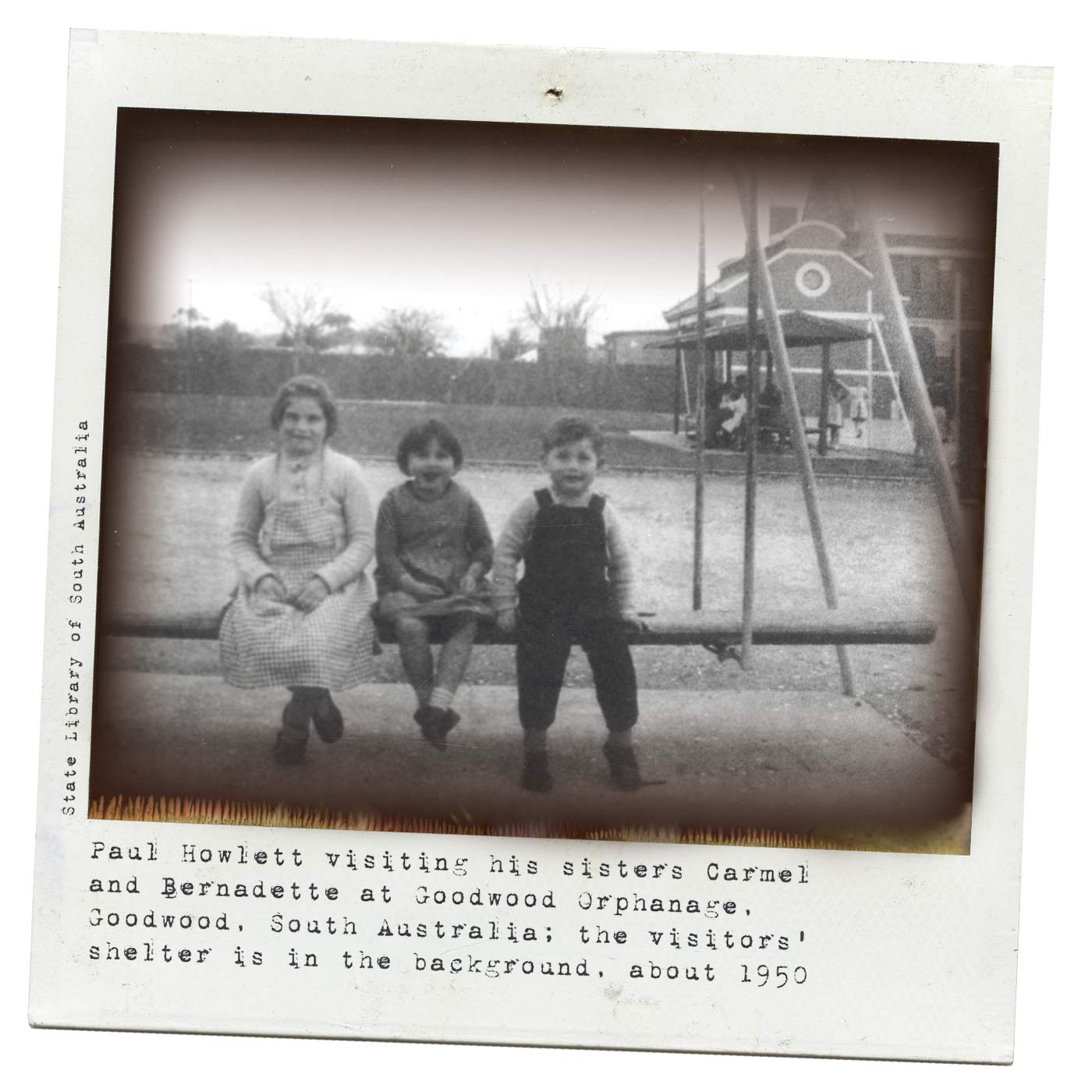 A black and white Polaroid photograph of three young children, two girls and a boy, sitting on a wooden swing. There is a building in the background and the children are smiling at the camera. Typewritten text underneath reads 'Paul Howlett visiting his sisters Carmel and Bernadette at Goodwood Orphanage, Goodwood, South Australia; the vistors' shelter is in the background, about 1950.' Smaller text, on the left-hand side of the image, in a vertical direction, reads 'State Library of South Australia'. - click to view larger image