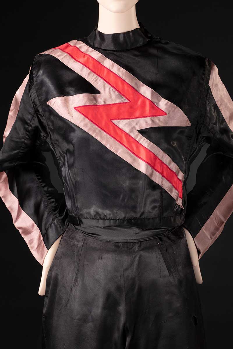 Black and salmon pink costume featuring a red lightning bolt motif, displayed on a mannequin. - click to view larger image
