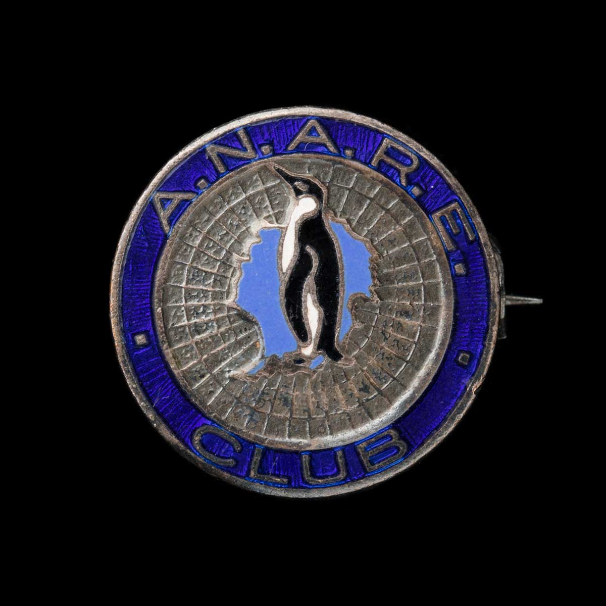 Metal badge for A.N.A.R.E Club featuring a penguin and map. - click to view larger image