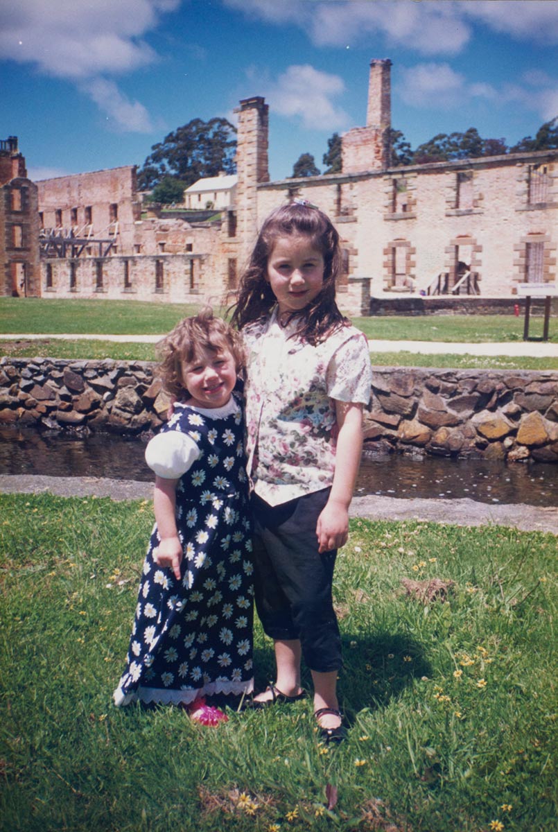 Two young girls pose together with ruins in the background. - click to view larger image