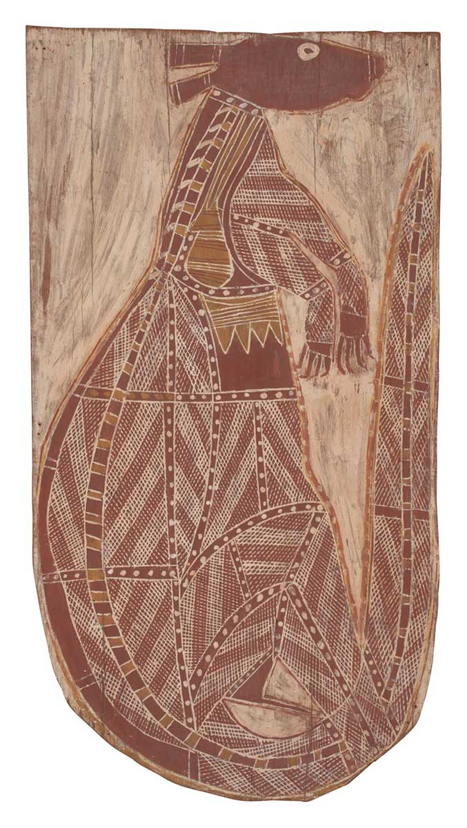A bark painting worked with ochres on bark. It depicts a kangaroo facing to the right with a brown head and white and brown crosshatching and dot design. The lower edge of the bark is rounded. The painting has a white background. - click to view larger image