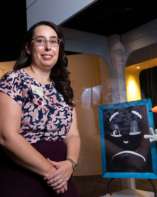 A photograph of curator Danielle Cassar with Blackboard. Danielle has black hair and is smiling at the camera.