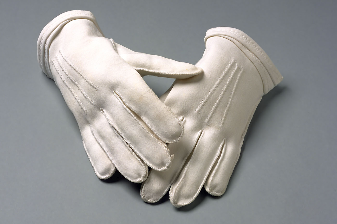 A pair of white fabric gloves. - click to view larger image