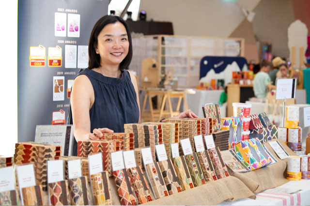 a woman stands behind a display of numerous blocks of chocolate. - click to view larger image