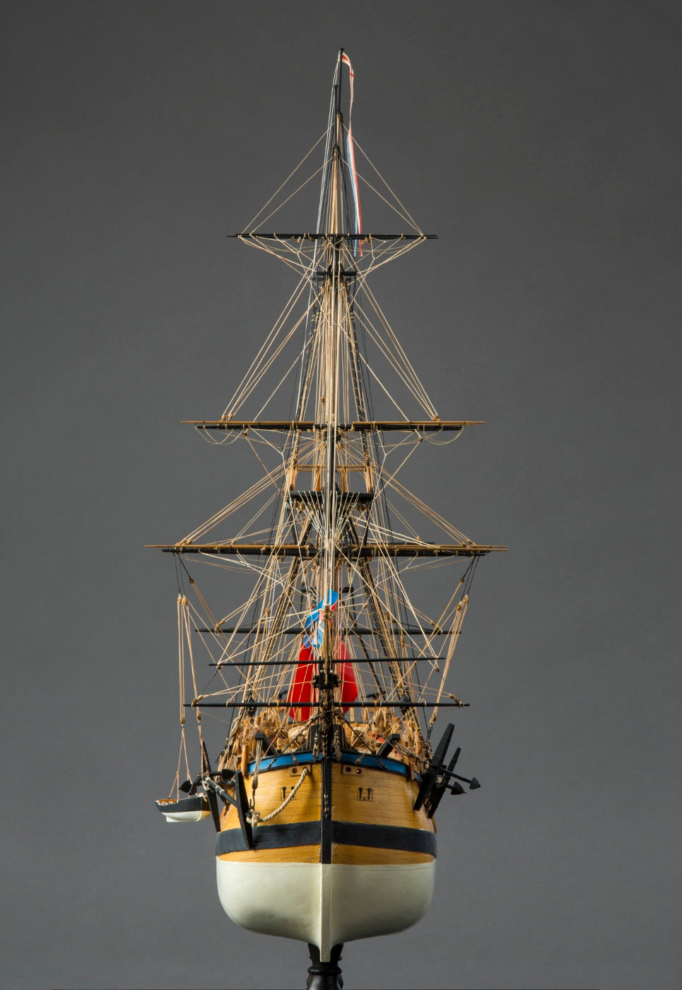 Front view of a model wooden sailing ship, with tall masts and rigging, and anchors at front either side. - click to view larger image