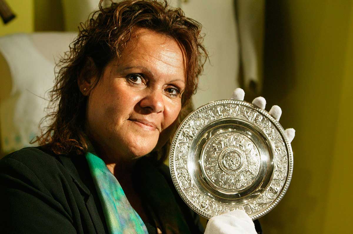 Evonne Goolagong Cawley, wearing white cotton gloves, holds a small silver plate. - click to view larger image