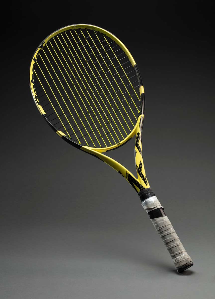 A yellow and black tennis racquet with grey textile wrapped around the handle.