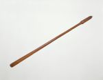 Staff made of brown wood, the grip end decorated with line and facial ornaments.