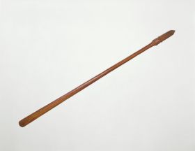 Staff made of brown wood, the grip end decorated with line and facial ornaments.