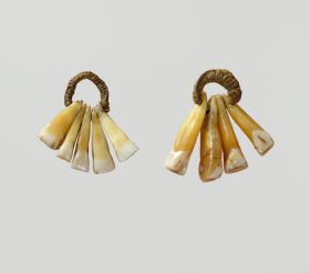 An ear-ornament formed of five human teeth strung on a plaited cord.