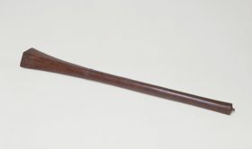 Club made of brown wood with a handle that is slightly rhomboid shaped at one end and pointed at the other. Both ends separated by a pair of bulged rings. A tiny knob on the bottom end.