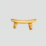 A small ornament made of bone carved in the form of a headrest.