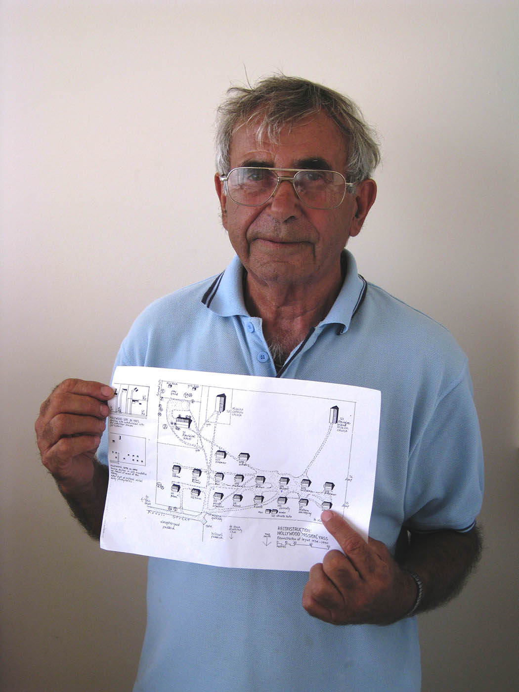 Eric Bell points to the bottom right corner of a sheet of A4 paper, marked with building locations. - click to view larger image