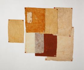 Samples of barkcloth some with a natural yellowish-white tone. Others featuring stamp patterns of red brown circles and another dyed yellowish-red and reddish-brown.