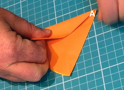 A large orange star cut out from orange paper. Two fingers point to two points on each side of the star.