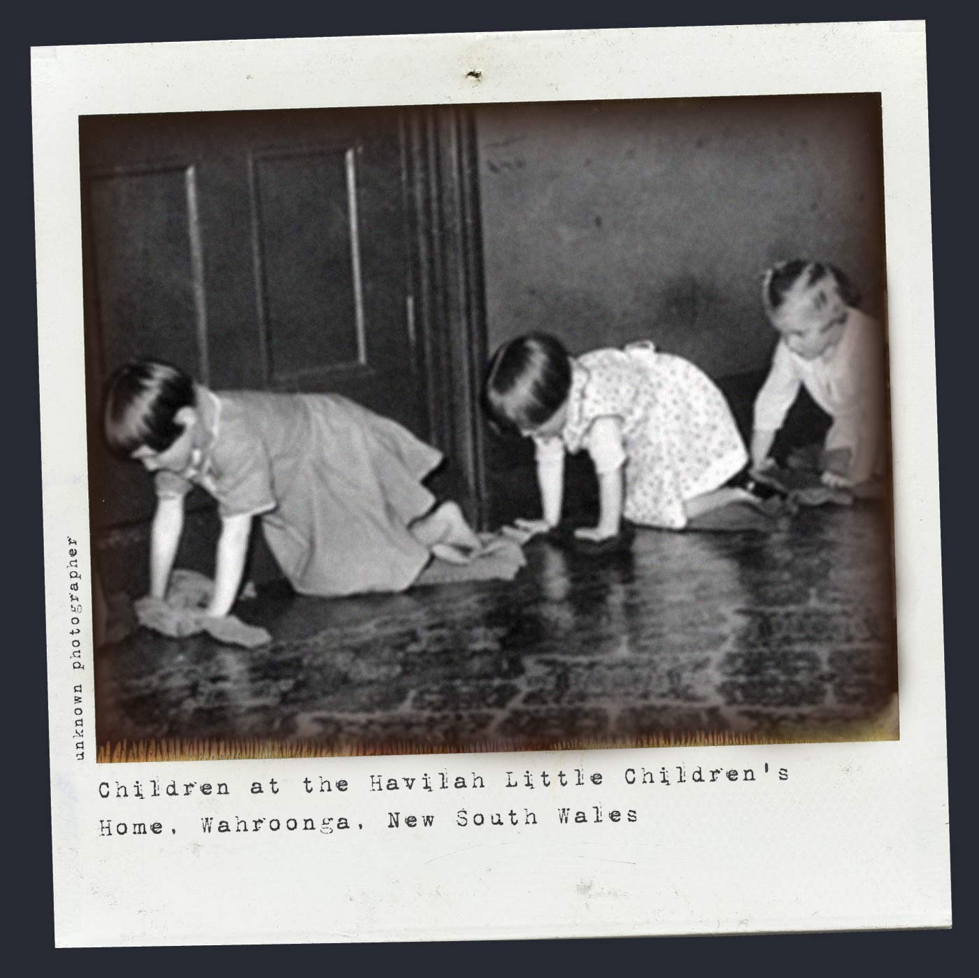 Polaroid photograph showing three girls, on hands and knees, polishing a floor. Typewritten text below reads 'Children at the Havilah Little Children's Home, Wahroonga, New South Wales'. 'Unknown photographer' is typed along the left side. - click to view larger image
