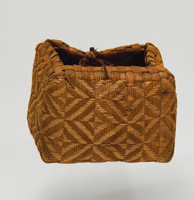 Basket made of pandanus leaves of yellowish and brown strips with a torn handle of plaited coconut fibre.