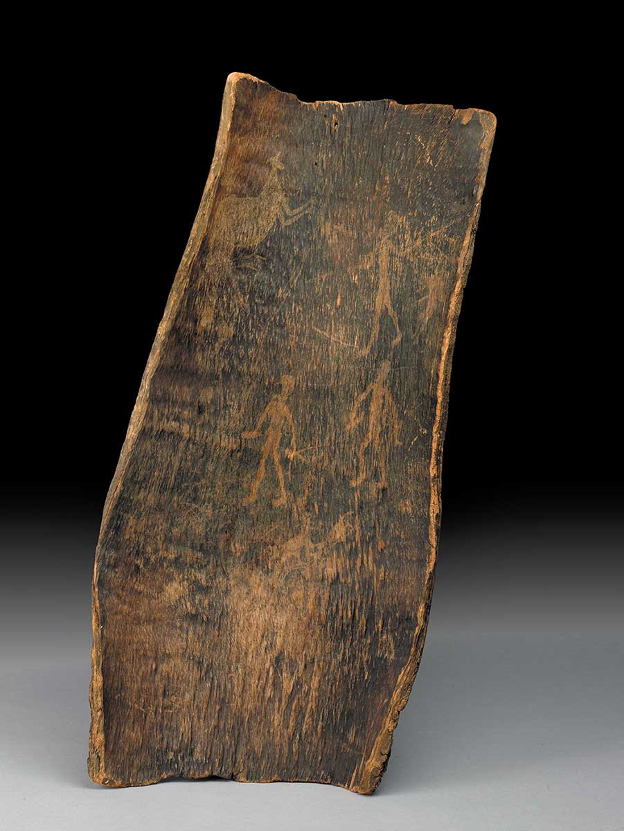 A piece of bark, blackened by fire, on which various figures have been etched, including a human figure pointing a spear at a kangaroo. - click to view larger image