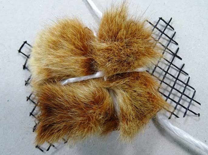 A necklace made by tying a scrap of possum fur to netting, using string. 