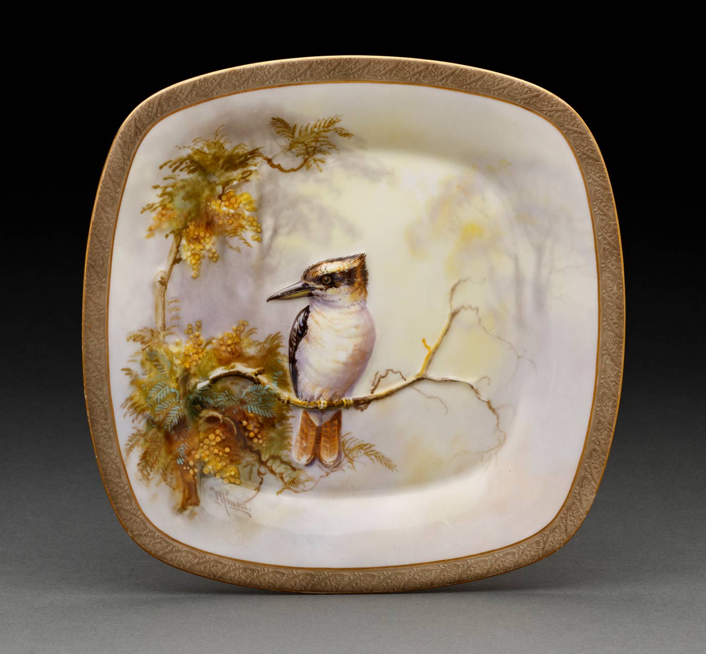 A white square plate embossed and painted with a Kookaburra sitting on a branch with yellow flowers and green leaves against a yellow and purple background, signed on left 'W POWELL' in brown, edges decorated with gold lines and a band of olive green lightly embossed with leaf design, paint missing in some areas. - click to view larger image