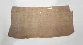 This piece of barkcloth, reddish-beige colour and full of holes around the edges.