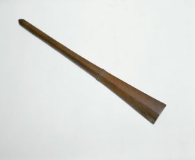 Club made of brown wood with a handle that is slightly rhomboid shaped at one end and pointed at the other. Both ends separated by a pair of bulged rings.