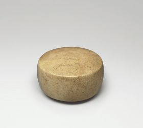 Gamestone made of stone and polished. Its formed into a round shape with flat sides.