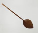 Paddle made of one piece of brown wood with an oval-shaped blade that is pointed at one end.