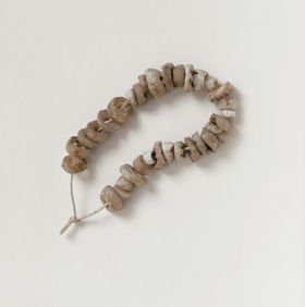 Jewellery & Adornment consisting of thirty-one white and beige-coloured shell discs arranged on a string.