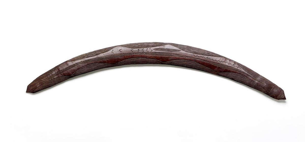 A wooden boomerang with pointed ends and engraved design.