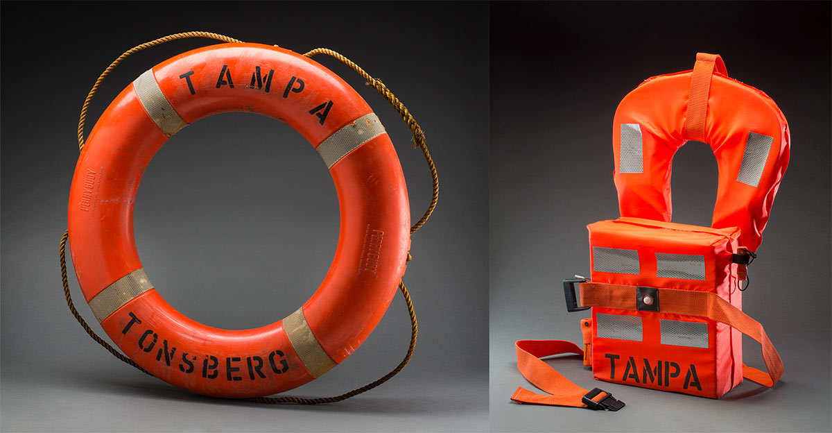 Orange lifejacket; orange lifebuoy with ‘Tampa’ painted on it.