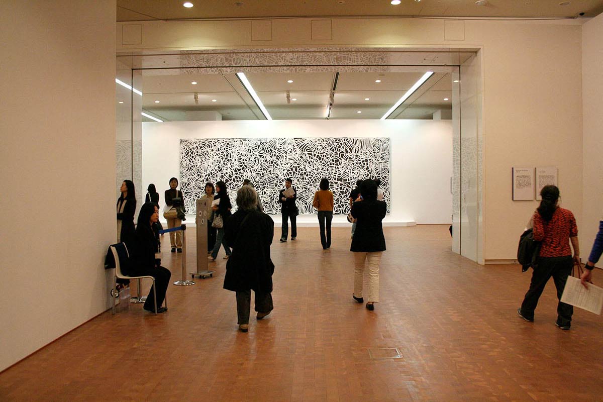 Visitors in an exhibition space viewing art works. - click to view larger image