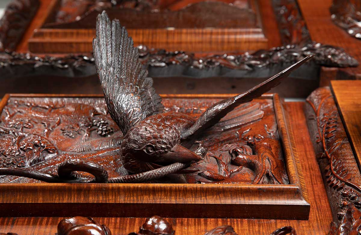 Detail of an ornate wooden panel of a relief carving of a bird with a snake in its beak. - click to view larger image