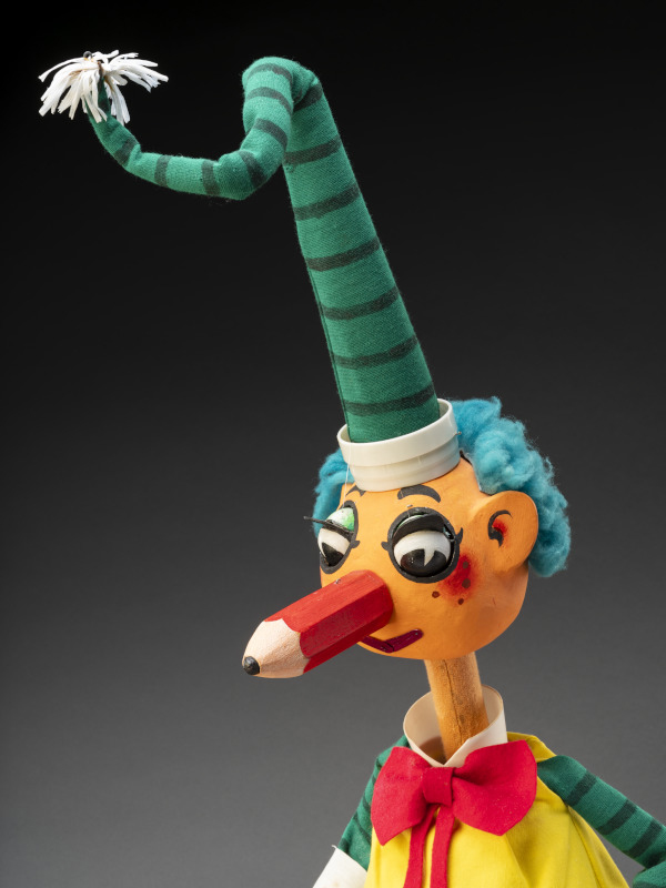 A close up photo of Mr Squiggles face and long pointy green and teal hat.